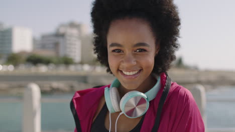retrato de una atractiva mujer afroamericana en ropa deportiva sonriendo alegremente en una hermosa playa soleada