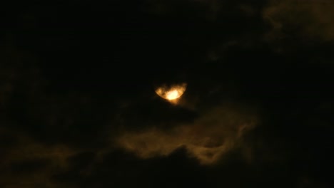 una luna emerge de una noche oscura envuelta en densas nubes - toma amplia