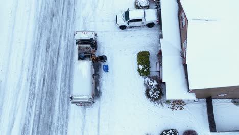 vista aérea de un camión volquete recogiendo basura en un día de nieve