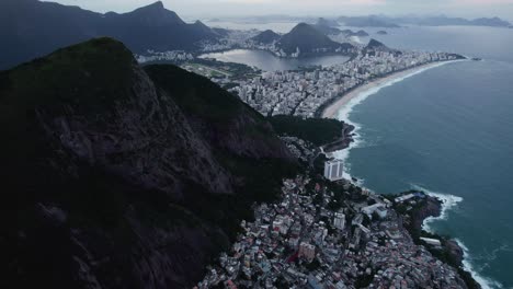 disparo de avión no tripulado pasando la montaña don irmaos hacia la playa de ipanema, noche sombría en río, brasil