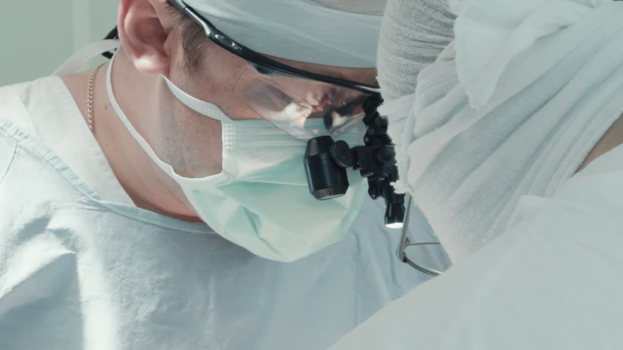전문적인 도구를 가진 외과 의사들이 수술합니다. 숙련된 의사들은 수술실에서 작은 동맥에 대한 관상동맥 바이파스 이식 수술을 수행합니다.