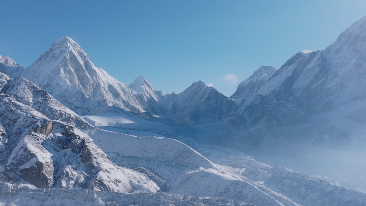 Drone flying over Everest Base Camp trek in Khumbu, Nepal. Morning sunlight reveals snow-capped 8000m Himalayan ranges below a clear blue sky, creating a breathtaking high-altitude scenic landscape