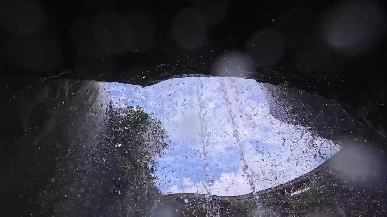 Uitzicht van achter een waterval omhoogkijkend naar de lucht