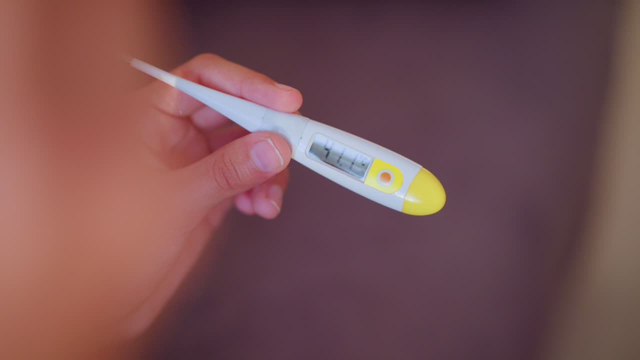 Close-up hand holding thermometer reading 41 C as person raises hand, showing high fever and discomfort, ideal for medical or health-related video projects