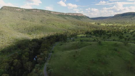 Green-Hills-With-Sky-Road-With-Creek,-Aerial