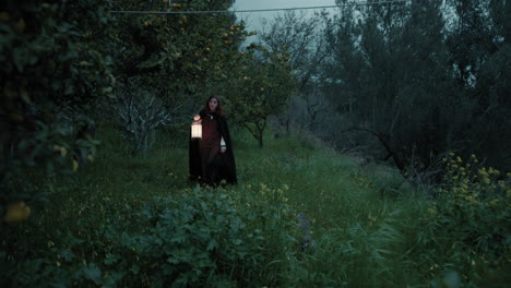 lonely woman walks in the forest at night with a lantern for spiritual rite