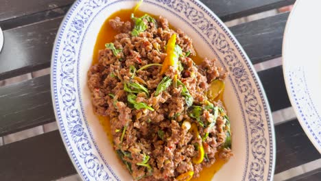 a vibrant thai dish with meat, rice, and vegetables on a decorative plate, captured in natural lighting