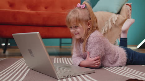 joyful school kid girl use laptop computer learning reading online education lessons alone at home