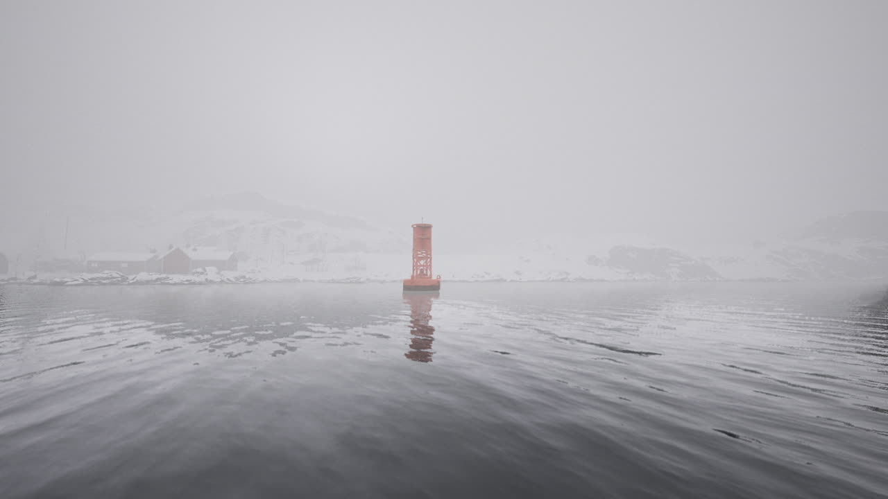 Foggy winter morning with a lighthouse standing in calm waters