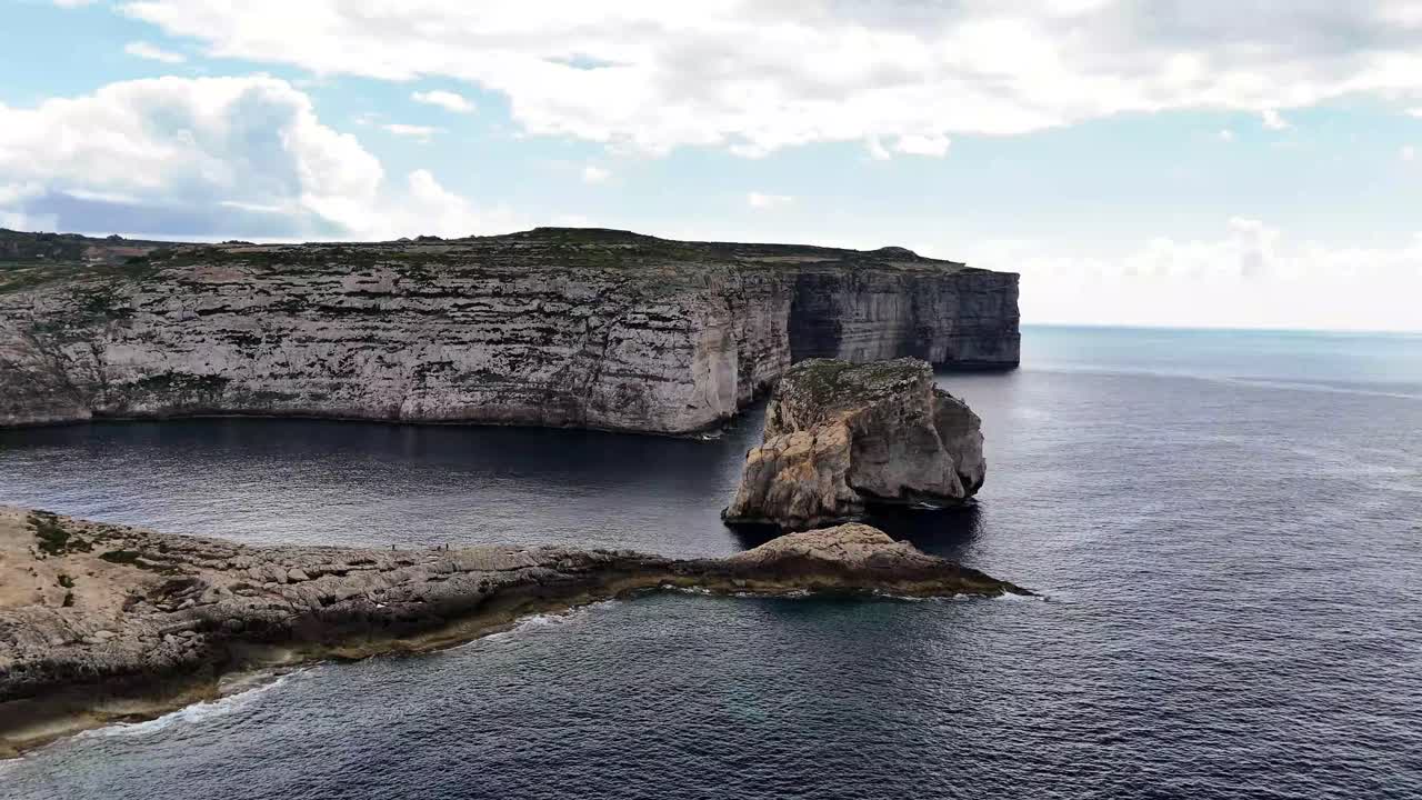 A high-altitude drone perspective of the limestone cliffs and Fungus Rock at Dwejra Bay in Gozo, Malta, surrounded by the deep blue Mediterranean Sea