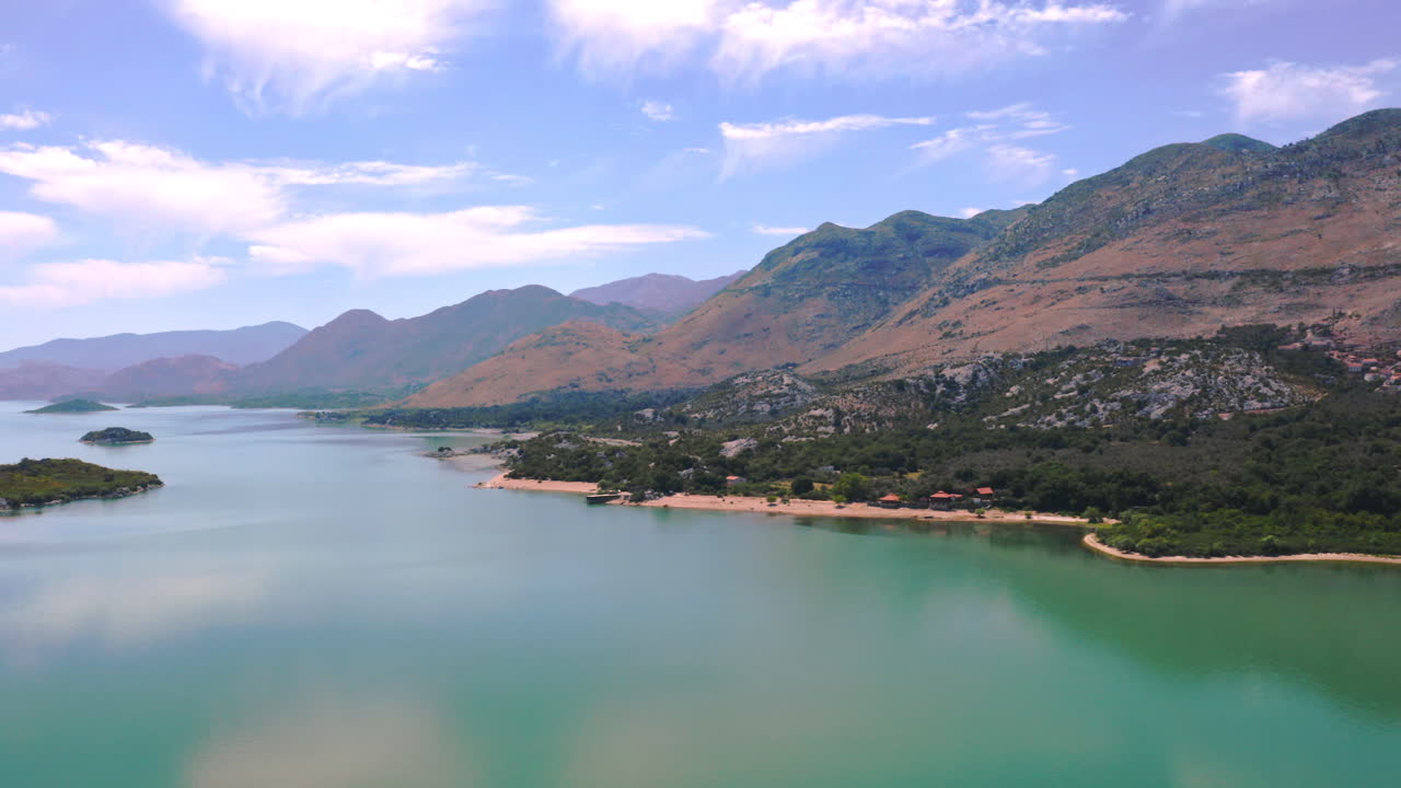 스카다르 호수, 몬테네그로, 그리고 흰 구름과 푸른 하늘을 반사하는 맑은 물과 호수 주변의 주변 산맥, 중간에 있는 작은 섬, 공중