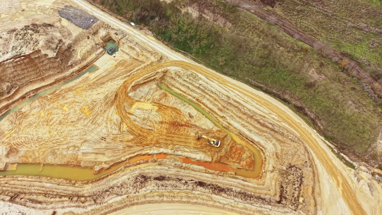 Construction site shows excavation work and land shaping in a rural area near water during daylight hours