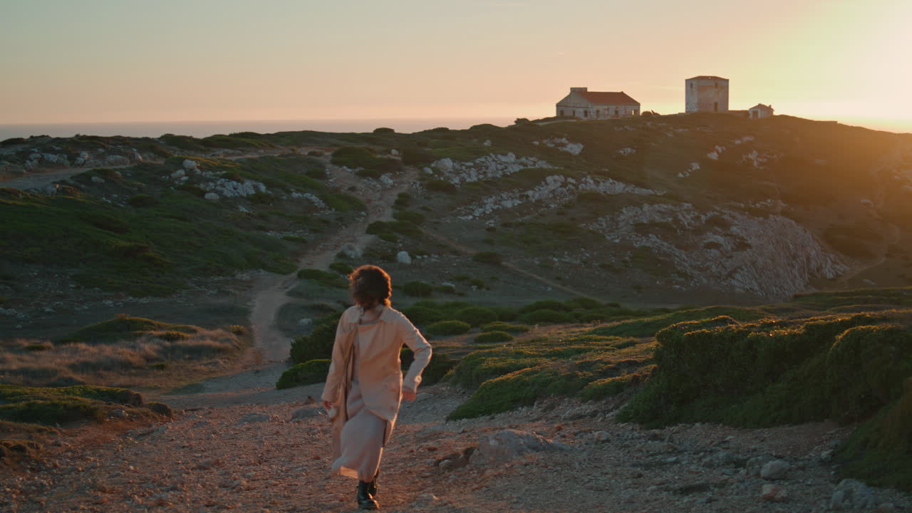 mujer alegre caminando por el camino del atardecer en el acantilado de la orilla del océano.