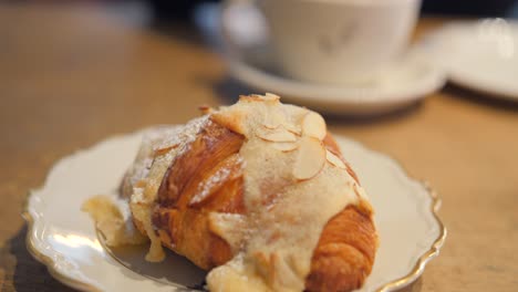 primer plano de un sabroso croissant de estilo sueco cubierto con almendras en un restaurante tradicional