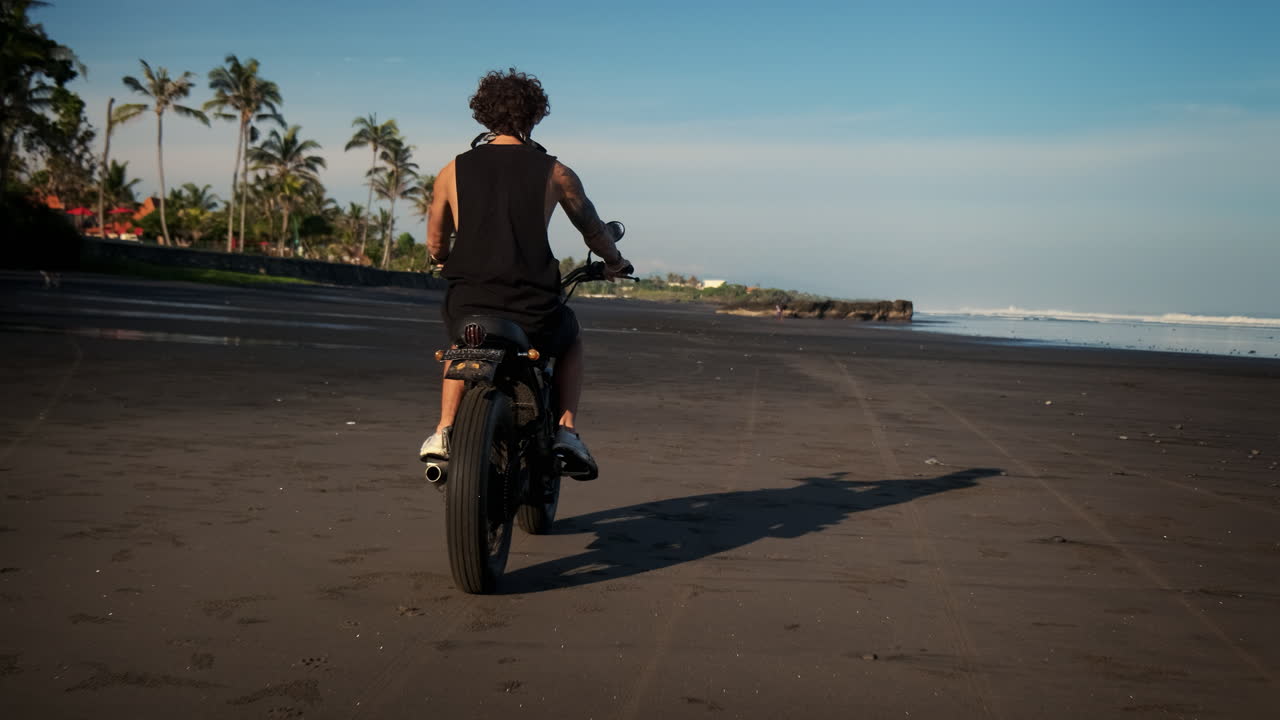 Uomo in moto su una spiaggia di sabbia nera