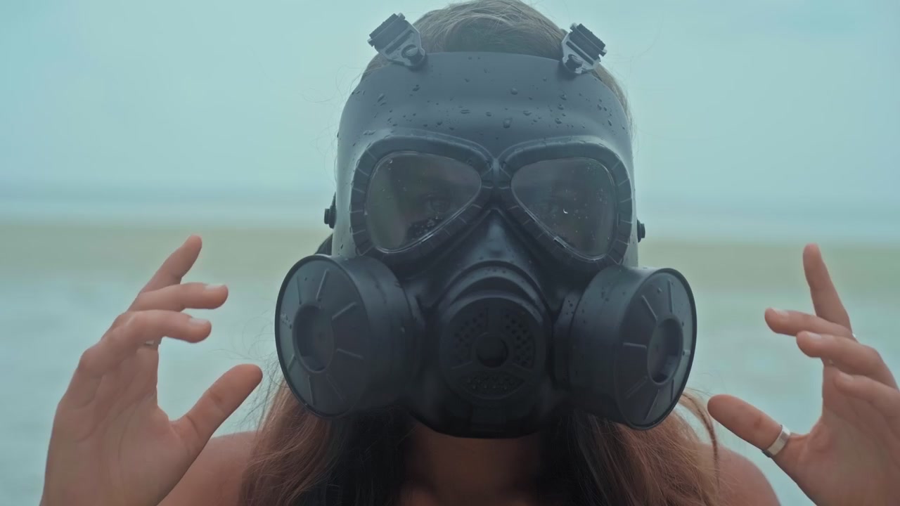 Young Woman Putting On A Gas Mask At The Beach