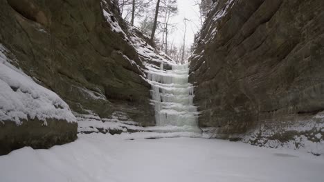 Frozen-cascading-water-over-cliff-side-in-steady-dolly-forward-view