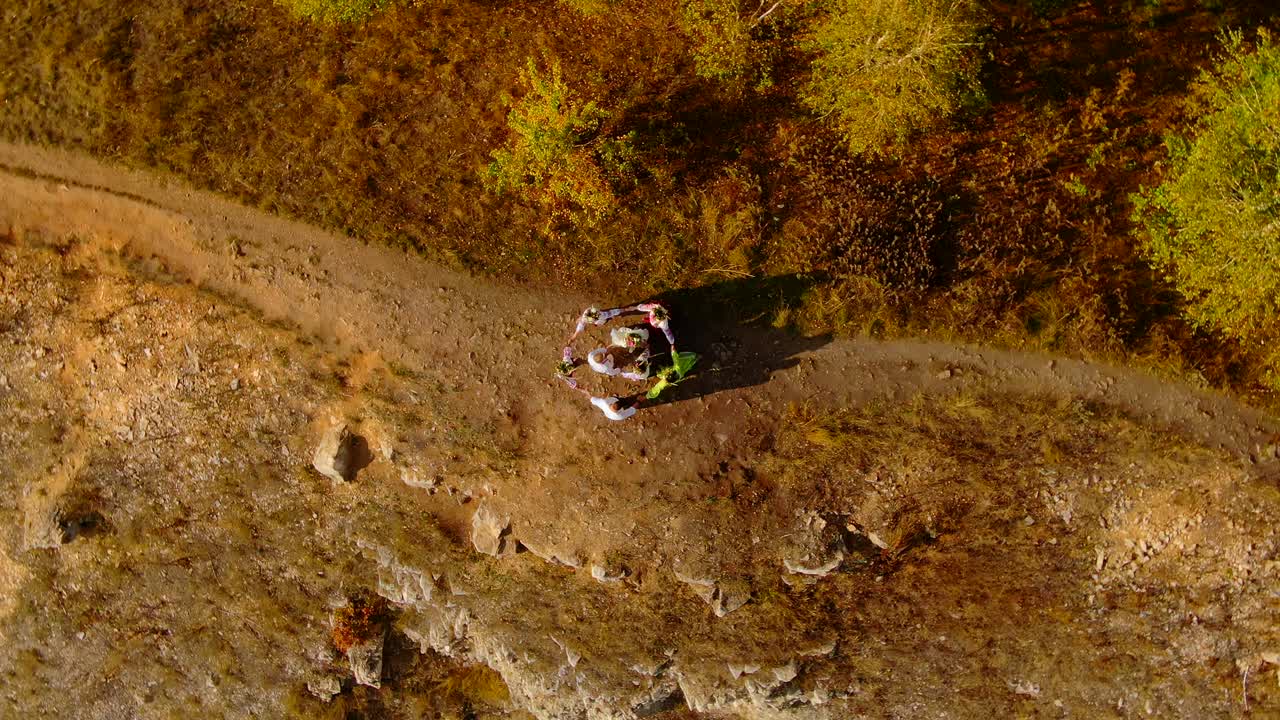 People in folk national costumes and dresses are dancing on the top of the hill, a beautiful view from the air. Men and women lead round dances and raise their hands up, traditions and rituals of the peoples. 4k, ProRes