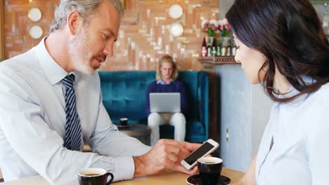 Woman-and-businessman-interacting-with-each-other-while-using-mobile-phone