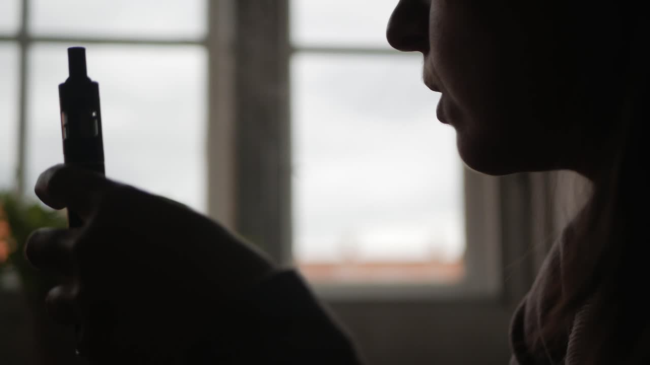 실내에서 전자 담배를 피우는 사람의 실루엣