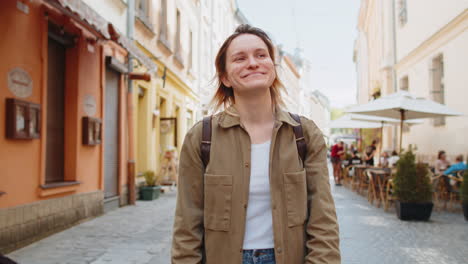 happy caucasian woman tourist traveler walking on urban city street good mood enjoying outdoors
