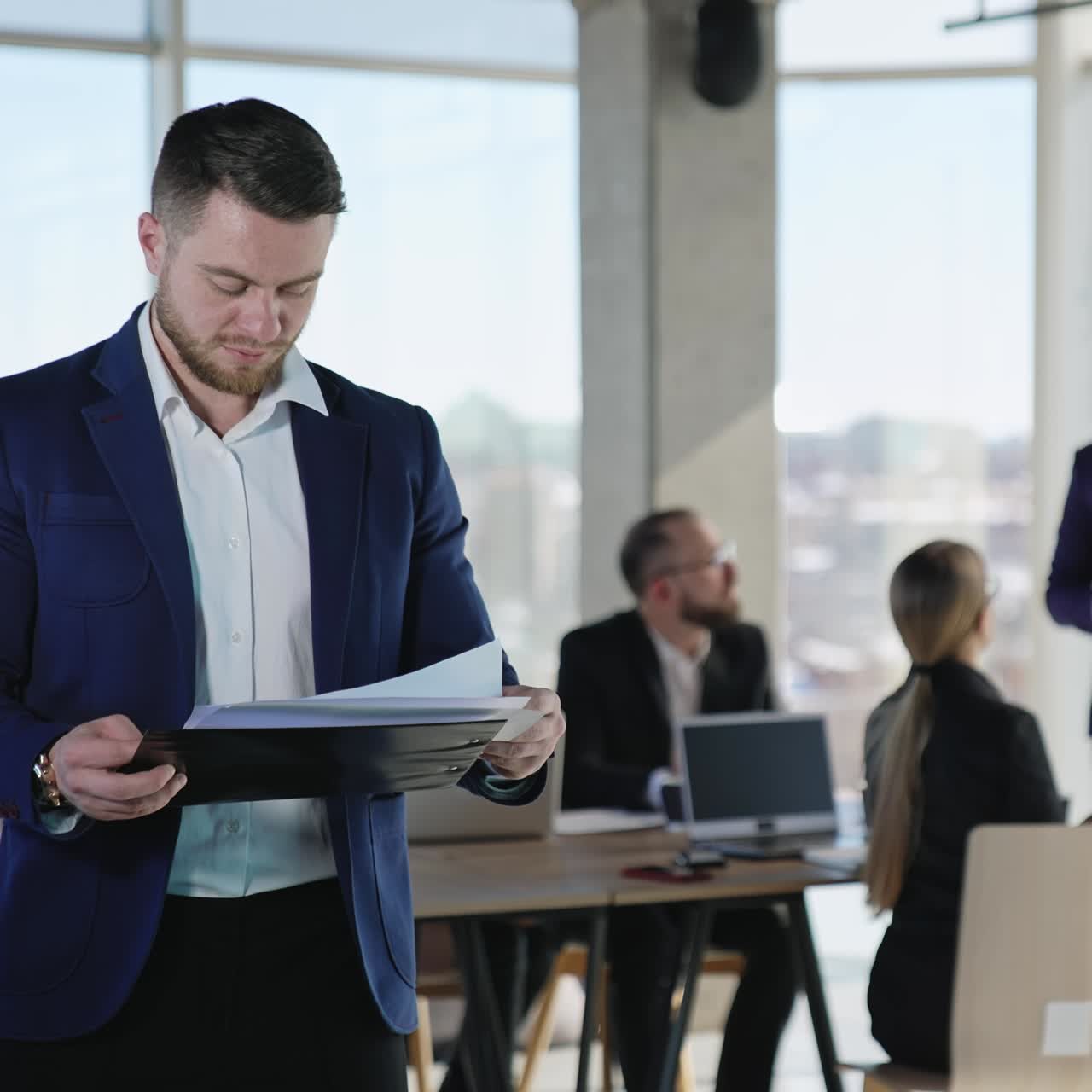 Young businessman looking through the business papers. Team of colleagues having business discussion at the table in the backdrop