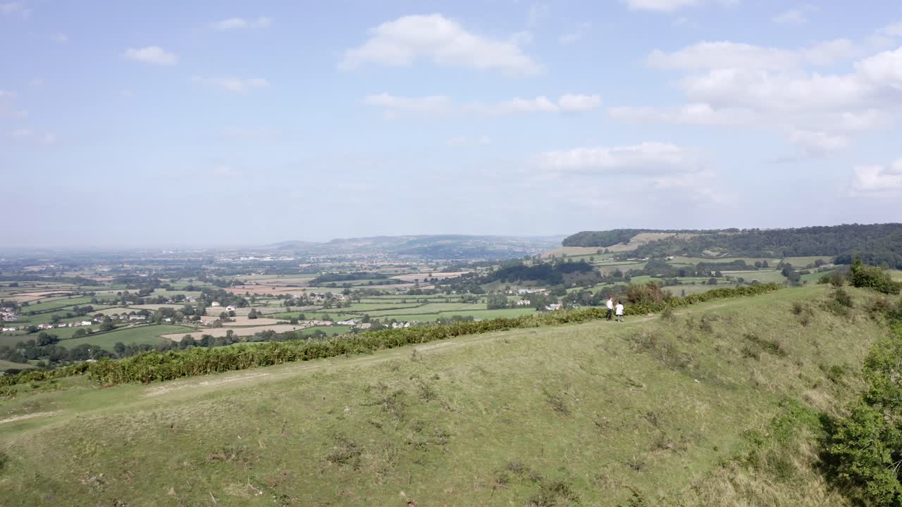 공중 - 부부는 uley, cotswolds, england, 트럭 오른쪽 근처 언덕에서 개를 산책시킵니다.