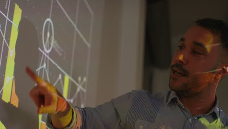 primer plano de un maestro masculino dando una lección de matemáticas o ciencias en la escuela de pie en la parte delantera de la clase con la proyección del gráfico 2