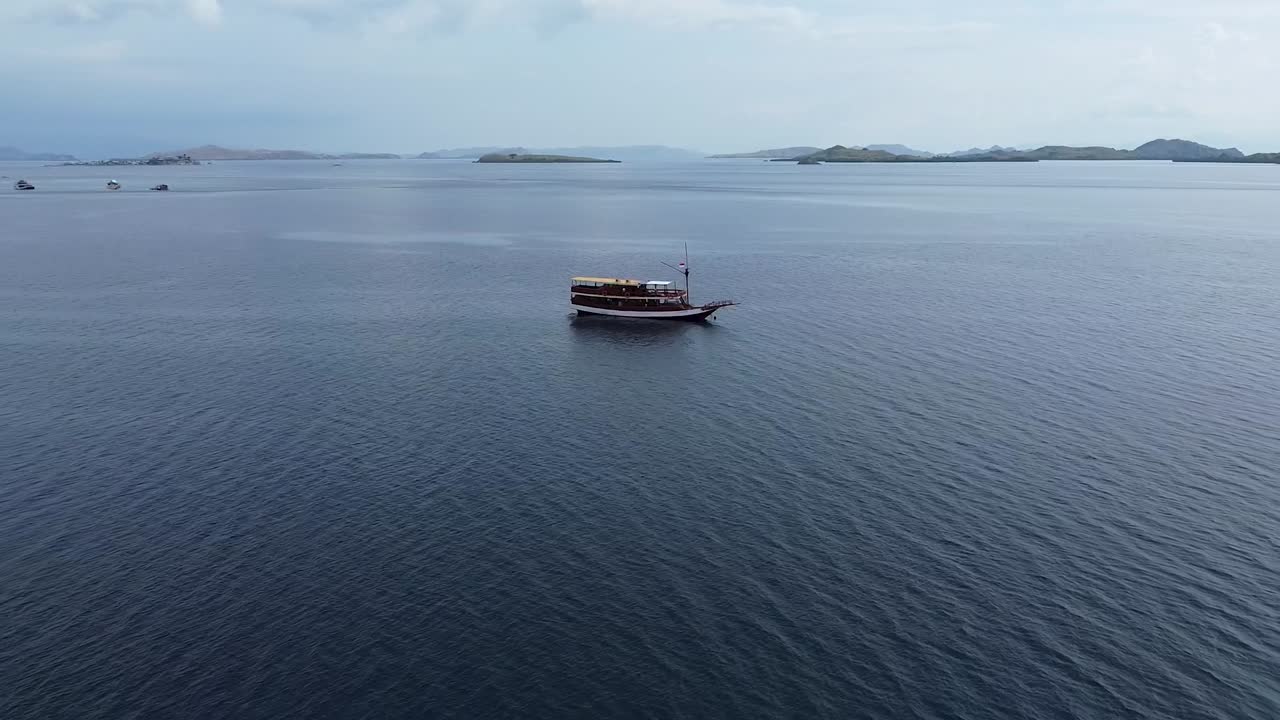 Pemandangan Udara Kapal Mengambang di Perairan Tenang di Lepas Pulau Komodo pada Hari Berawan