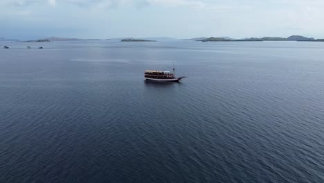 Vista-Aérea-Del-Barco-Flotando-En-Aguas-Tranquilas-Frente-A-La-Isla-De-Komodo-En-Un-Día-Nublado