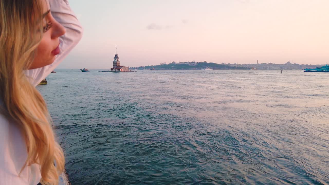 rallentatore: la bella ragazza gode della vista del tramonto sul bosforo con vista della torre della fanciulla sullo sfondo a istanbul