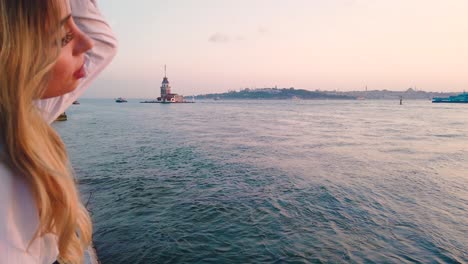 slow motion:beautiful girl enjoys sunset view of bosphorus with view of maiden tower at background in istanbul