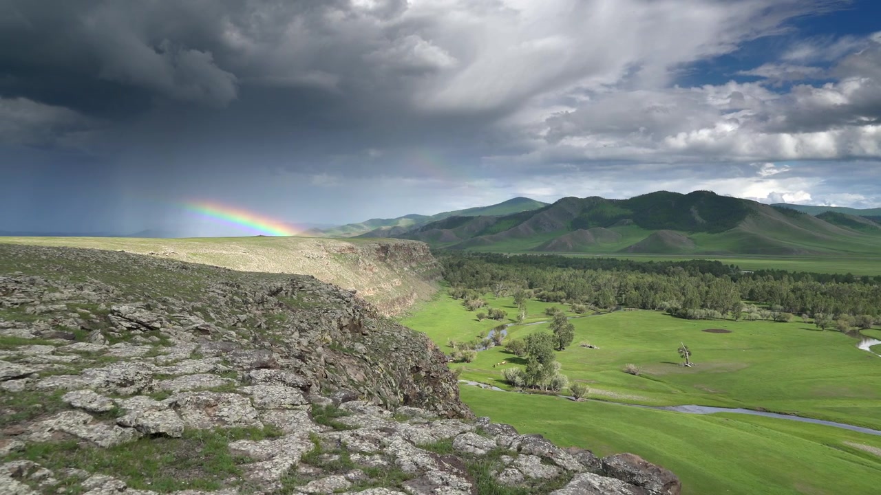 Paesaggio suggestivo con valle verde e arcobaleno sotto un cielo tempestoso