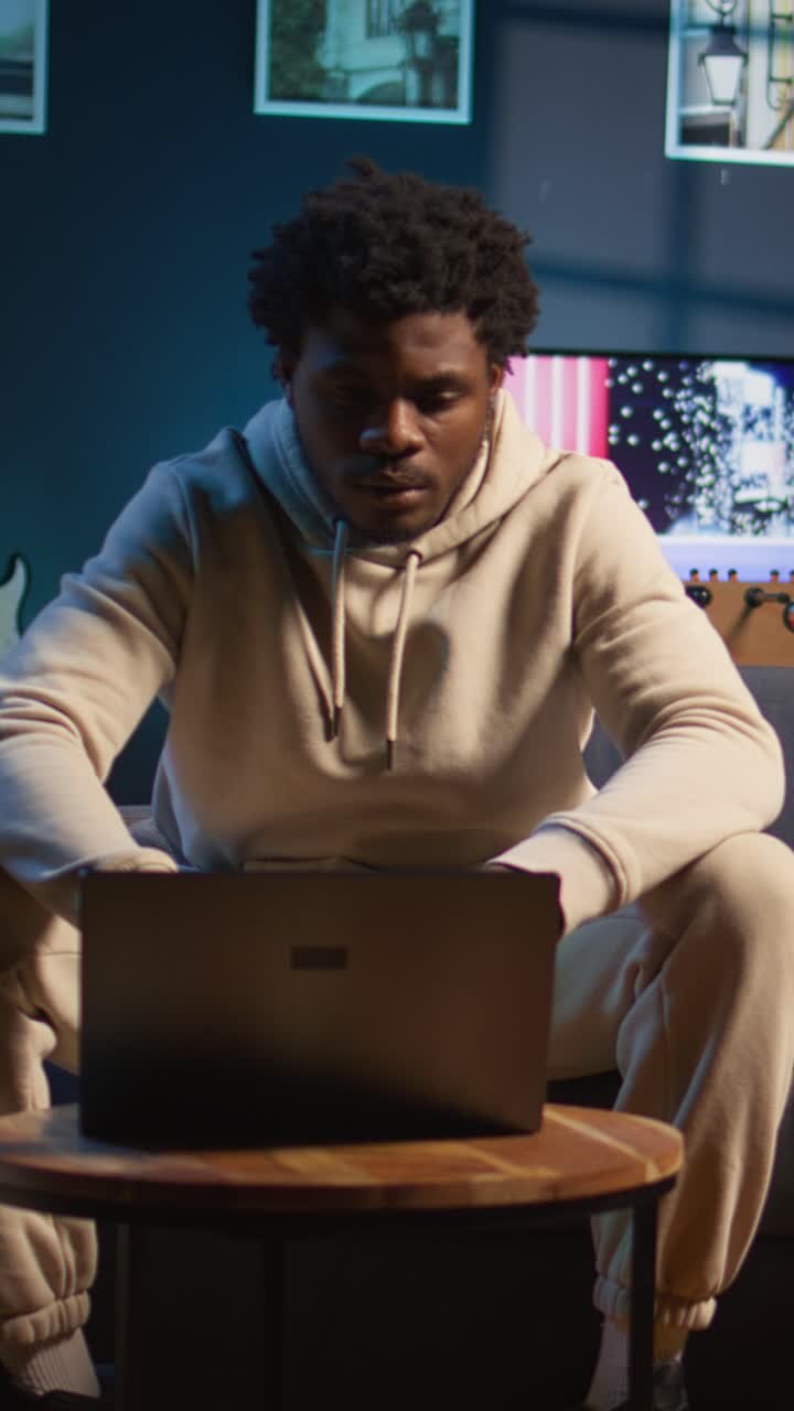 Young African American Man Typing on Laptop in Living Room