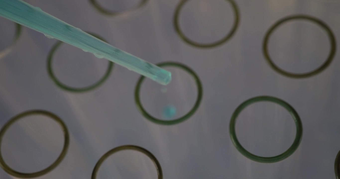 Gocce di liquido blu che cadono da una pipetta in numerose provette
