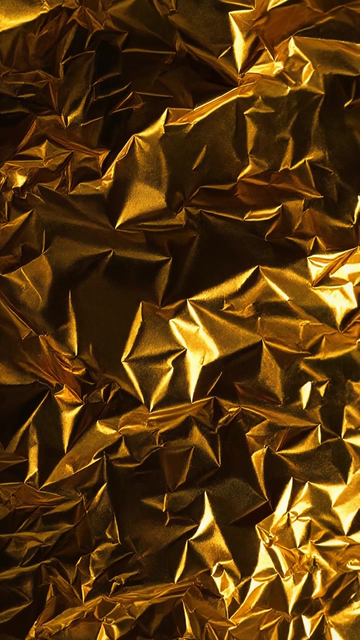 Sfondo astratto di materiale in foglia d'oro stropicciata con riflessi metallici scintillanti