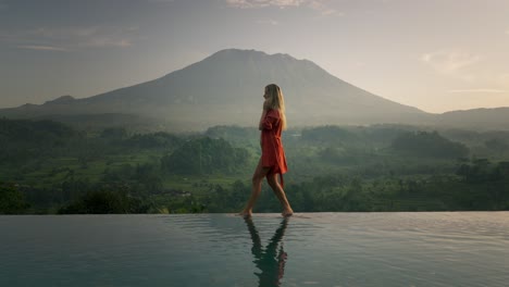 attractive blond digital nomad woman on morning business phone call in bikini, volcano agung