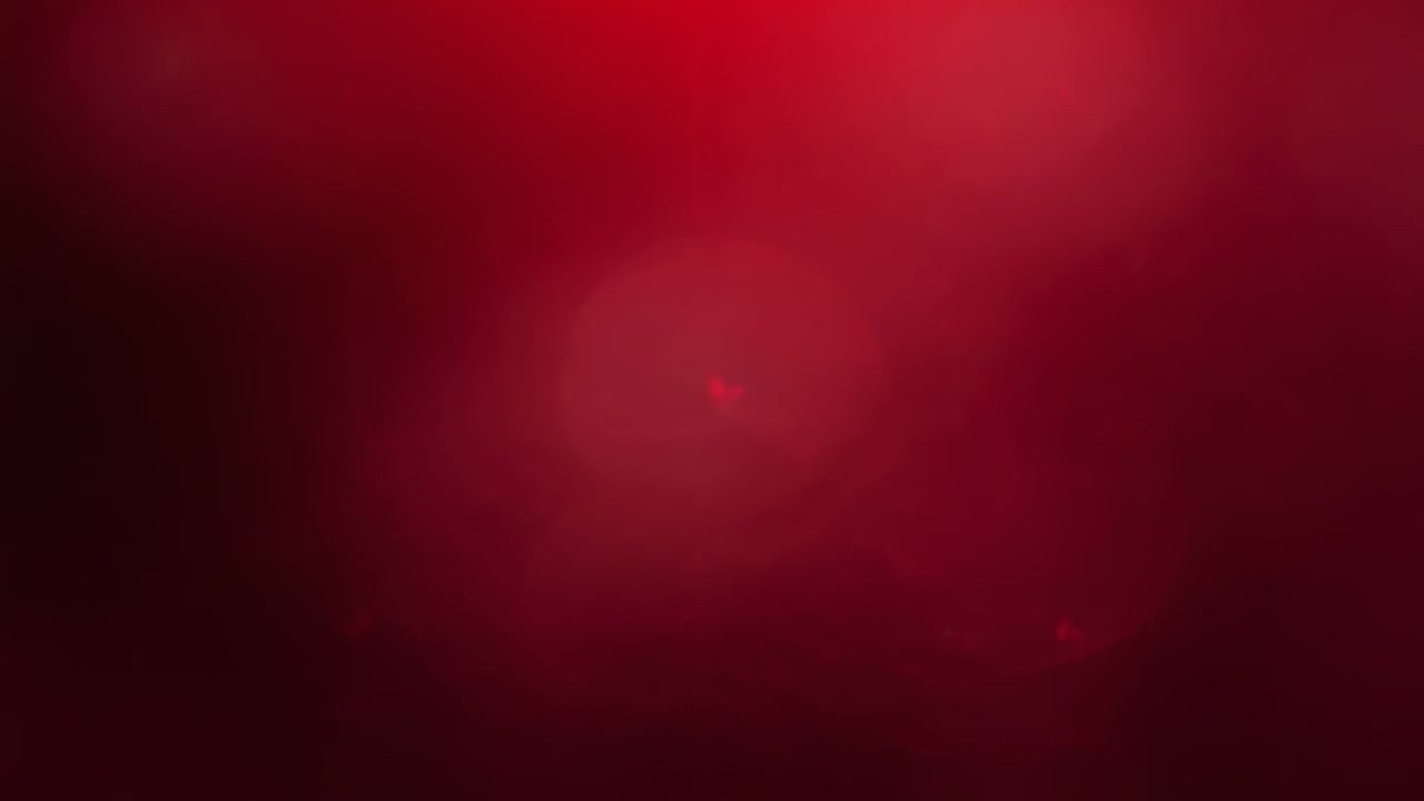 Brightening red glow spreading as frames advancing in dark frame, with lens-flare pinpoint visible