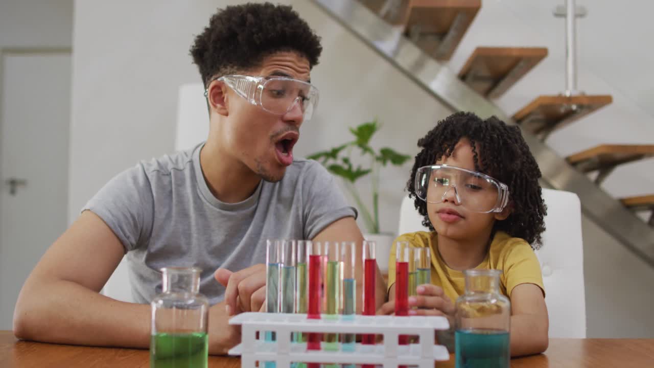 feliz hombre biracial y su hijo haciendo experimentos de química