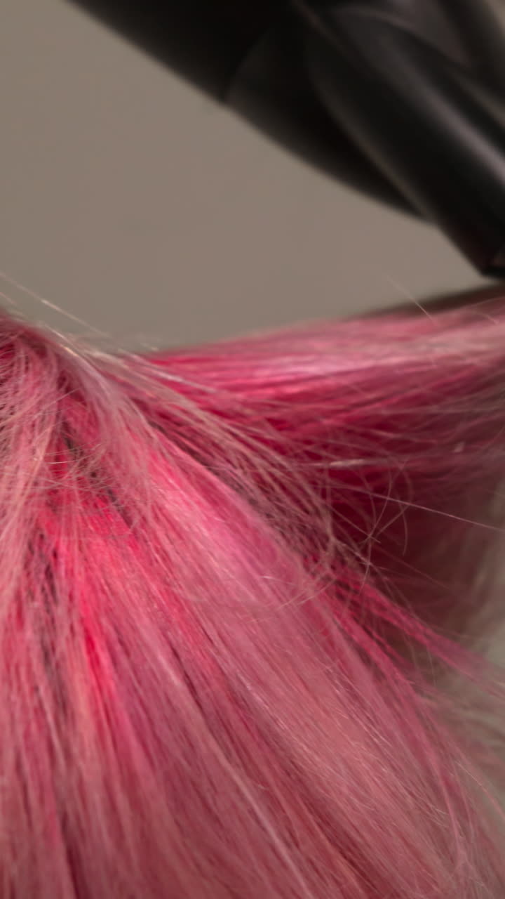 Primer plano de mano secando y estilizando cabello rosa vibrante