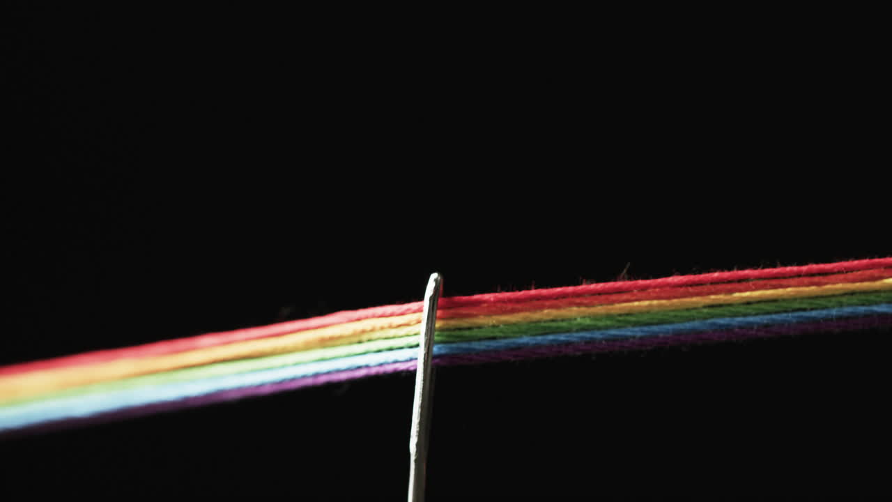 video de micro de hilos de color arco iris que pasan a través de la aguja con espacio de copia en fondo negro