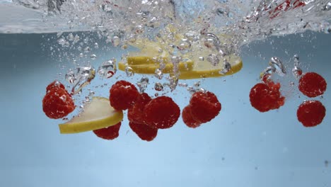 frambuesas y limones golpeando la superficie del agua