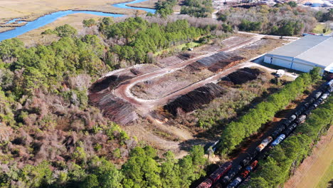 Aerial-footage-rotating-around-a-water-sprinkler-over-a-large-pile-of-logs-at-a-paper-making-plant-that-is-beside-a-group-of-trains