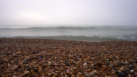 4k of sea and waves on a peddle beach during a foggy day.