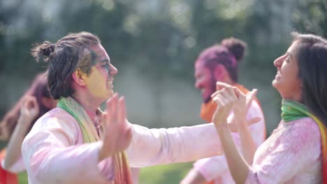 una pareja india bailando en una fiesta de holi en un parque