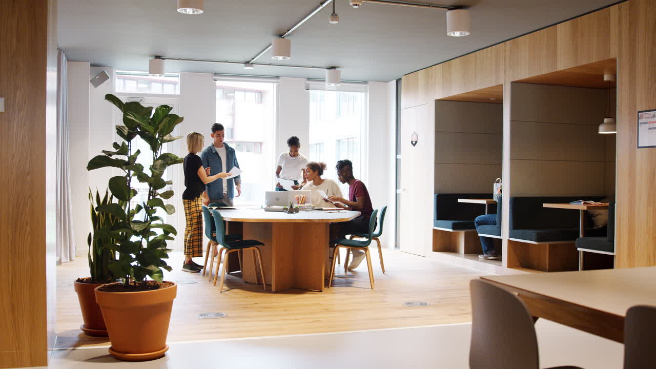 Millennial creative team in discussion at a creative meeting around a table in a large office space