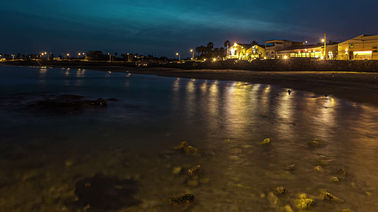 luces brillantes de la ciudad por la noche y el mar con la playa en sicilia, italia, lapso de tiempo