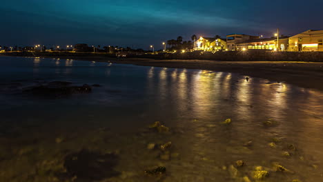 Leuchtende-Stadtlichter-Bei-Nacht-Und-Meer-Mit-Strand-In-Sizilien,-Italien,-Zeitraffer