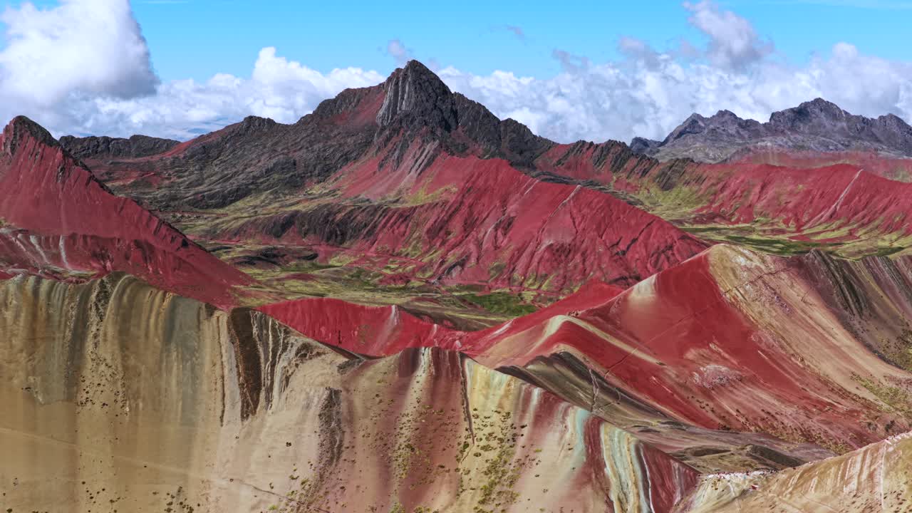Rainbow Mountain Vinicunca Peru Perú aerial drone morning blue sky Montaña de Siete Colores Palccoyo clouds Peruvian Andes Red Valley striped hills seven colored Cusco Region backwards pan up motion