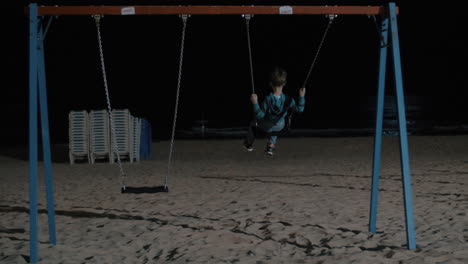 Niño-Solitario-Balanceándose-En-La-Playa-Por-La-Noche